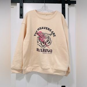 Cream “THE HEAVENS ARE ROARING” sweatshirt.